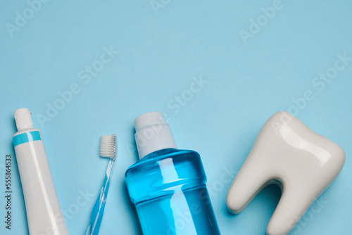 A toothbrush with toothpaste and oral rinse on blue background