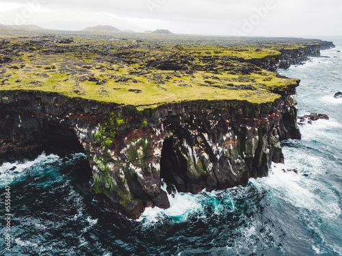 Spectacular black volcanic rocky ocean coast with cave arch and towers - Iceland photo