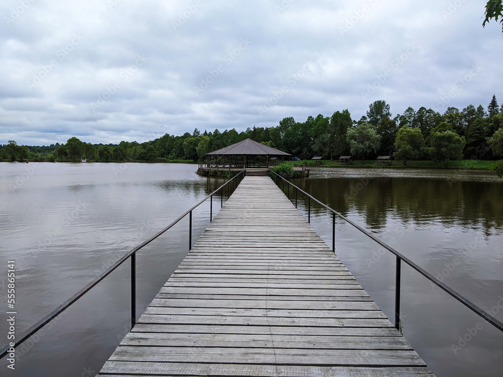 Naklejka premium Wooden gazebo in the pier on the river with water in the background.