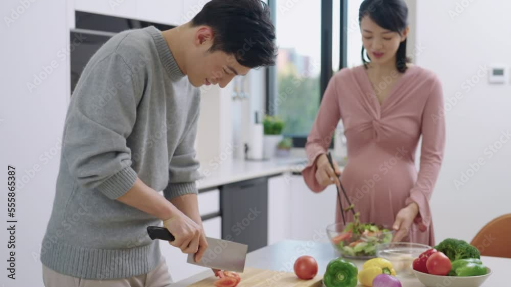 Young pregnant Chinese couple cooking food Young pregnant Chinese couple cooking food