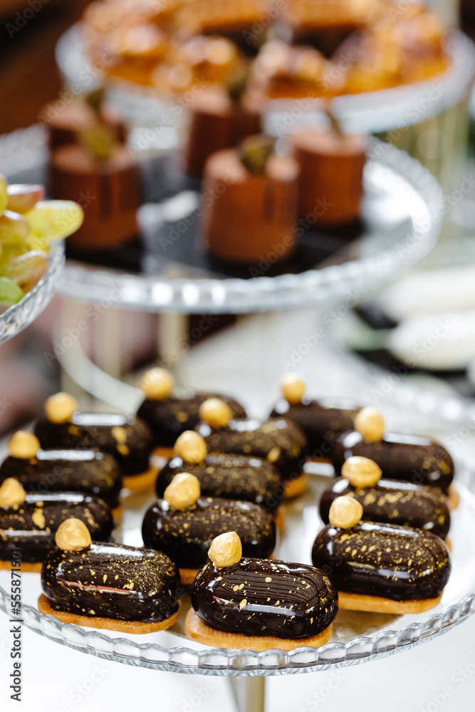 A variety of eclairs with chocolate glaze and nuts on the festive table