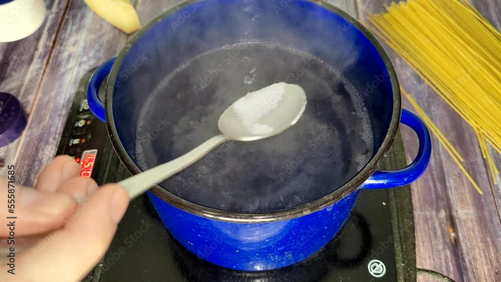 Boiling water on an induction stove. Adding salt to boiling water Stock