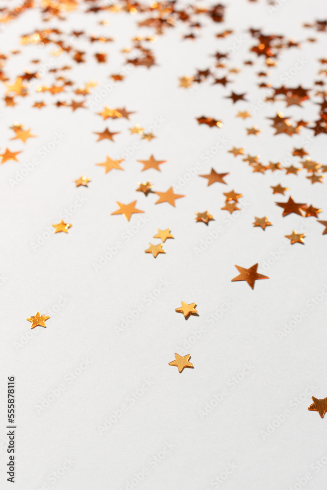 Shiny golden stars confetti scattered on a blue pastel background. Selective focus.