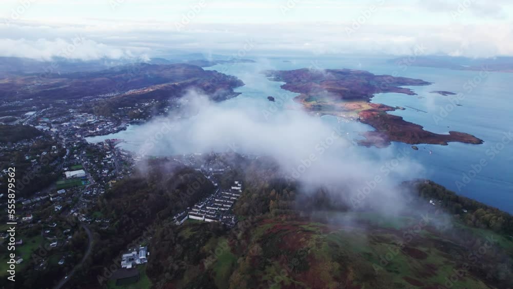 High aerial drone shot of town of Oban in Scotland, flying through clouds reveal High aerial drone shot of town of Oban in Scotland, flying through clouds reveal