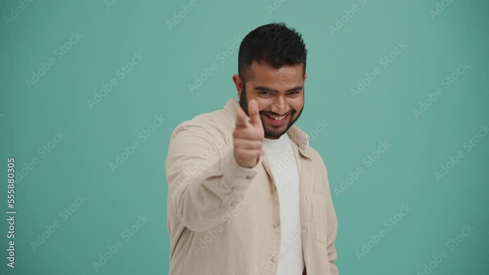 Happy Middle Eastern young man pointing finger at the camera in the turquoise studio Happy Middle Eastern young man pointing finger at the camera in the turquoise studio