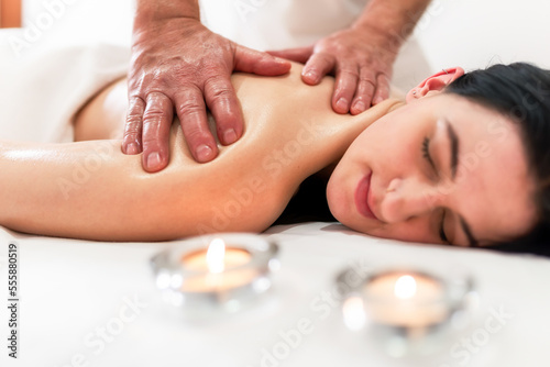 Masseur massaging back and shoulder blades of young woman lying on massage table on white background. Concept of massage spa treatments