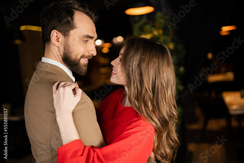 happy man and woman in festive attire hugging while looking at each other on valentines day