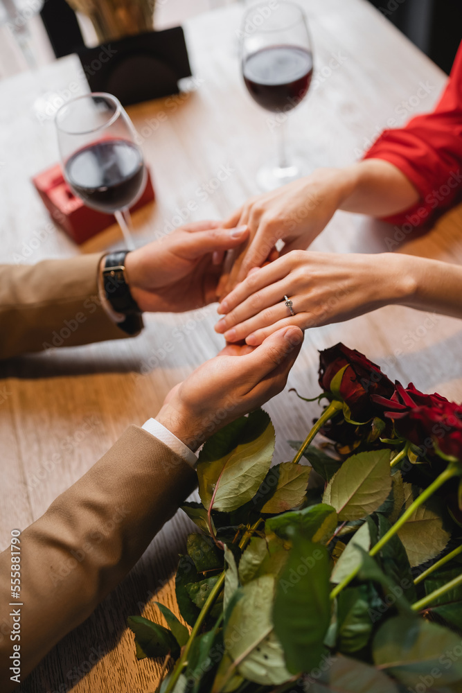 Obraz premium cropped view of woman with engagement ring on finger holding hands with boyfriend on valentines day