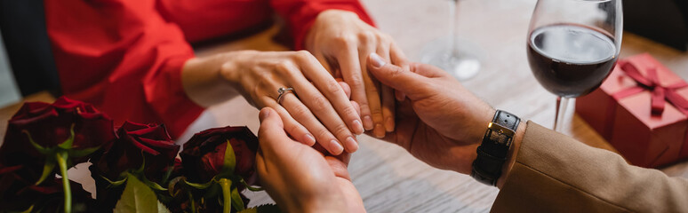 cropped view of woman with engagement ring on finger holding hands with man on valentines day, banner