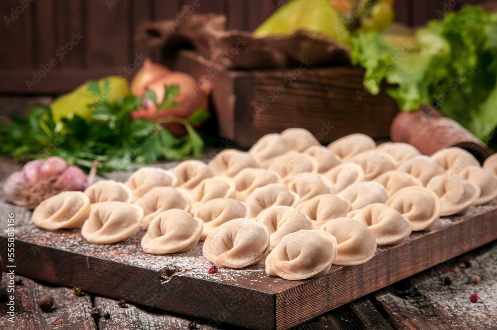 Meat dumplings - russian pelmeni on wooden background