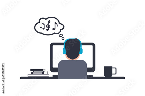 man at work back view. young man with desktop computer listening music wearing headphones