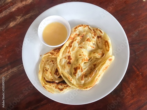Abstract process photo of Roti canai with a cup of condensed milk as a sweet recipe in Thailand. That also calls roti prata which is an Indian flatbread dish can be cooked sweet or savoury variations