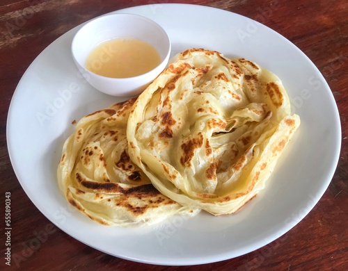 Abstract process photo of Roti canai with a cup of condensed milk as a sweet recipe in Thailand. That also calls roti prata which is an Indian flatbread dish can be cooked sweet or savoury variations