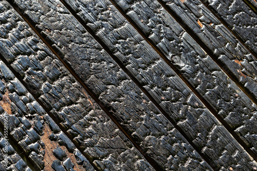 Black wooden board texture, close up. BBQ background. Burnt wooden Board texture. Burned scratched hardwood surface. Smoking wood plank background. Burned wooden grunge texture