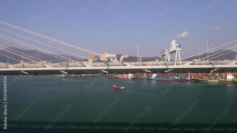 Drone shot of traffic on Stonecutters Bridge during sunny day in Hong Kong - Industrial Harbor with container ships in background Drone shot of traffic on Stonecutters Bridge during sunny day in Hong Kong - Industrial Harbor with container ships in background