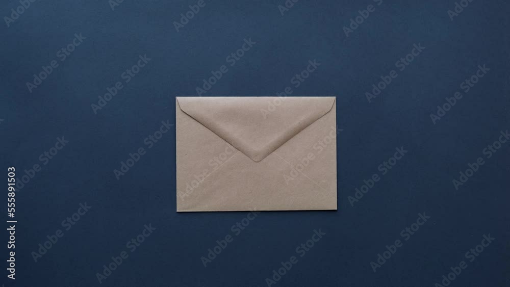 Woman's hand puts a craft mail envelope on a dark table top view
