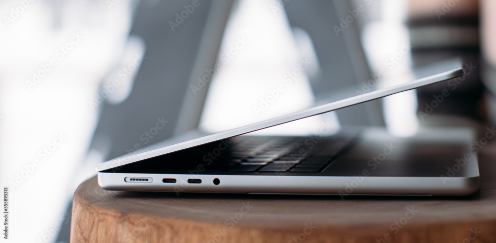 magsafe 3. Macbook pro 14 2021. magnetic charger charges laptop on wood background. USB-C to MagSafe 3 Cable Gray laptop on the table. winter outside the window magsafe 3. Macbook pro 14 2021. magnetic charger charges laptop on wood background. USB-C to MagSafe 3 Cable Gray laptop on the table. winter outside the window