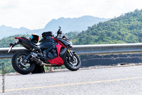 Red motorcycle modern style parked on road with mountain view background and copy space