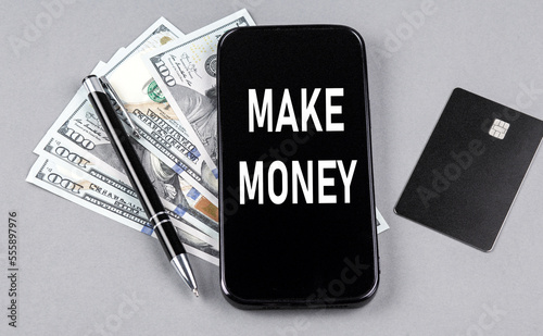 Credit card and text MAKE MONEY on smartphone with dollars and pen. Business concept