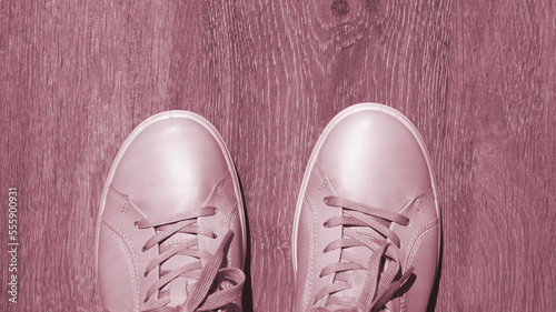 Viva magenta banner of light pink sneakers close-up on a wooden background. Top view