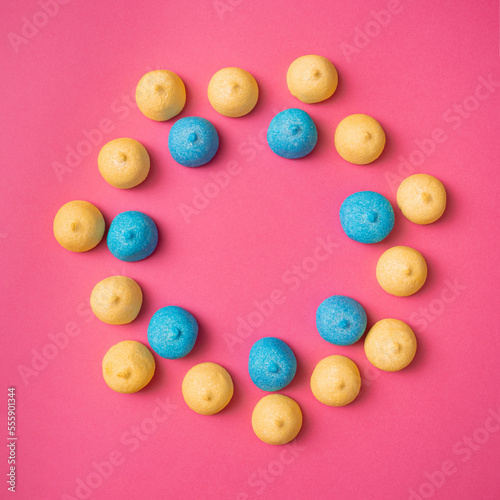 Optimistic round pattern of yellow and blue marshmallows on a pink background. Delicious holiday candies for parties and picnics. Abstract fun pattern with copy space, flat lay