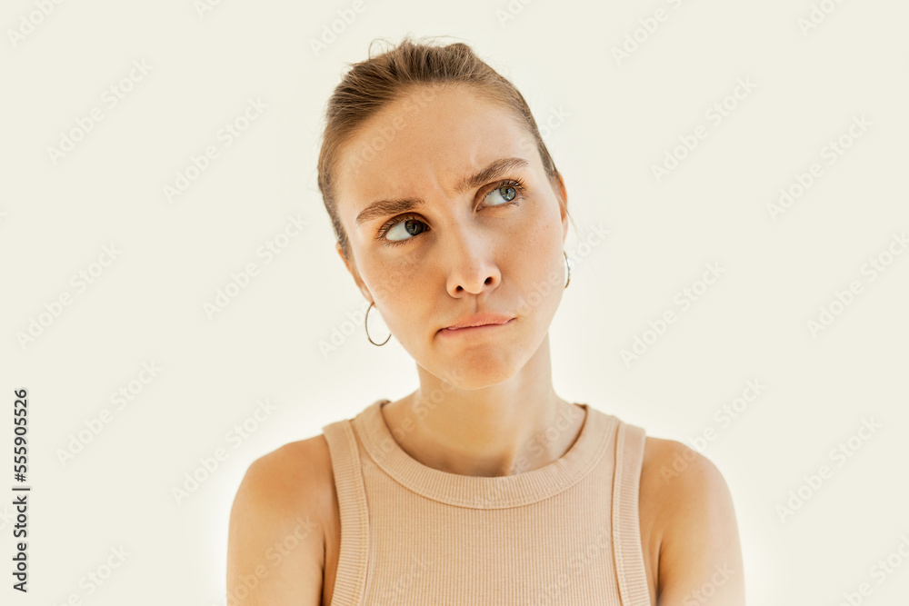 Head shot of pretty puzzled perplexed female frowning curving her lips with hmm facial expression, looking up aside with thoughtful look, having dilemma, isolated on white studio background Head shot of pretty puzzled perplexed female frowning curving her lips with hmm facial expression, looking up aside with thoughtful look, having dilemma, isolated on white studio background