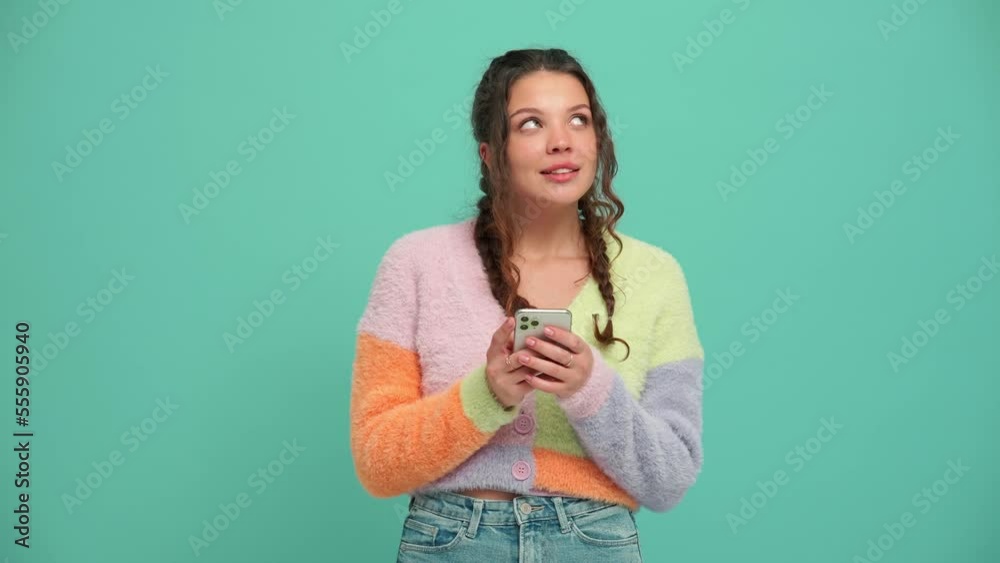 Lovely young woman with pigtails typing on mobile in the turquoise studio Lovely young woman with pigtails typing on mobile in the turquoise studio