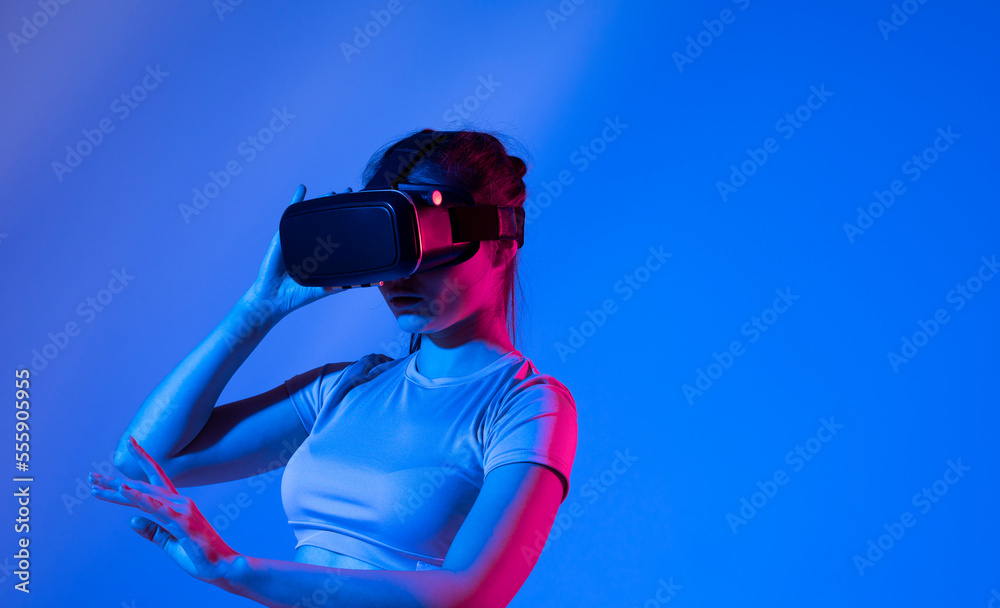 Young cute woman wearing a virtual reality googles and playing a video game in virtual world with a friends. Young cute woman wearing a virtual reality googles and playing a video game in virtual world with a friends.