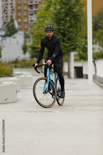 A cyclist in black sportswear on a blue gravel bike.