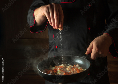 Fototapeta Naklejka Na Ścianę i Meble -  The cook adds salt to a steaming hot pan. Menu idea for a hotel with advertising space. Asian national cuisine. Restaurant menu or recipe. Copy space