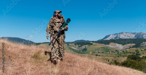 Army soldier holding a sniper rifle with scope and walking in the forest. war  army  technology and people concept.