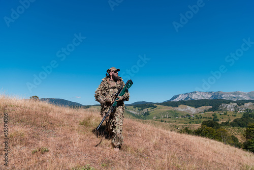 Army soldier holding a sniper rifle with scope and walking in the forest. war  army  technology and people concept.