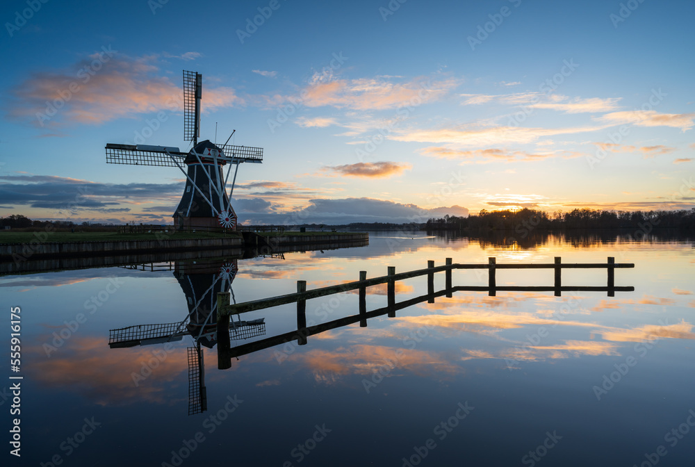 Traditional Dutch windmill during a tranquil and sunset in winter.