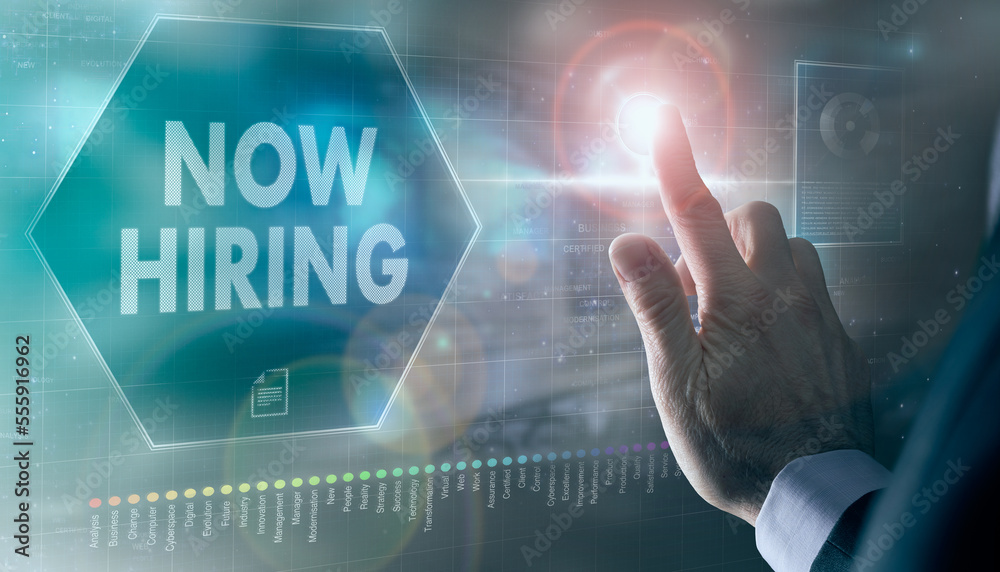 A businessman controlling a futuristic display with a Now Hiring business concept on it.