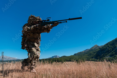 Army soldier holding a sniper rifle with scope and walking in the forest. war, army, technology and people concept.