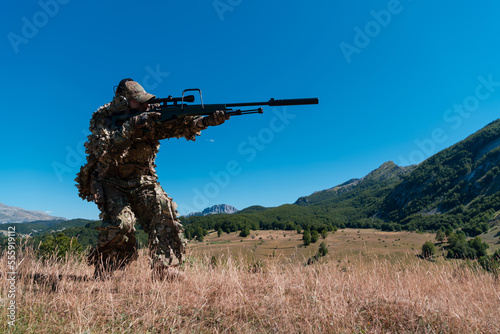 Army soldier holding a sniper rifle with scope and walking in the forest. war, army, technology and people concept.