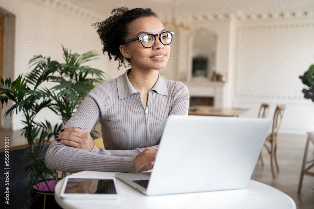 A young smart woman with glasses, a freelancer in an office workplace, a laptop computer on the table for online work on a startup. A young smart woman with glasses, a freelancer in an office workplace, a laptop computer on the table for online work on a startup.