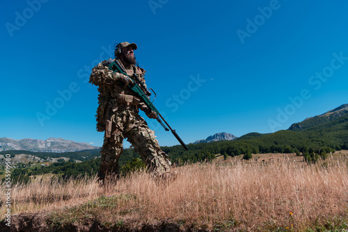 Army soldier holding a sniper rifle with scope and walking in the forest. war  army  technology and people concept.