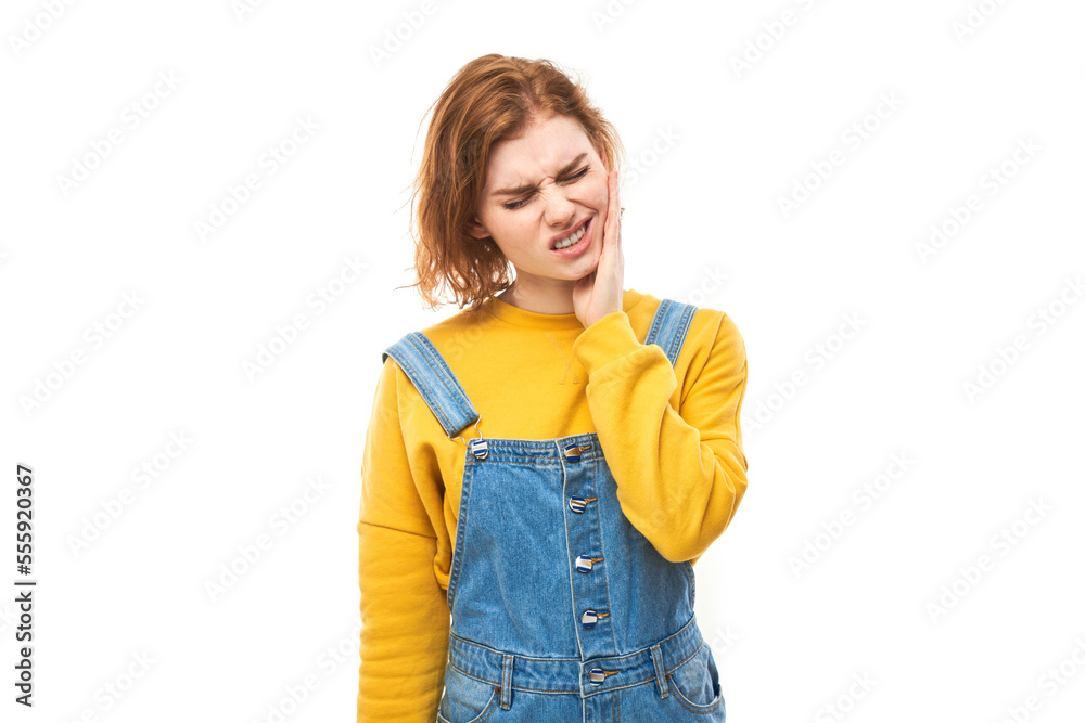 Young redhead woman with suffering face expression holds cheek with hand, touching mouth with palm isolated on white background. Toothache, dental pain concept Young redhead woman with suffering face expression holds cheek with hand, touching mouth with palm isolated on white background. Toothache, dental pain concept