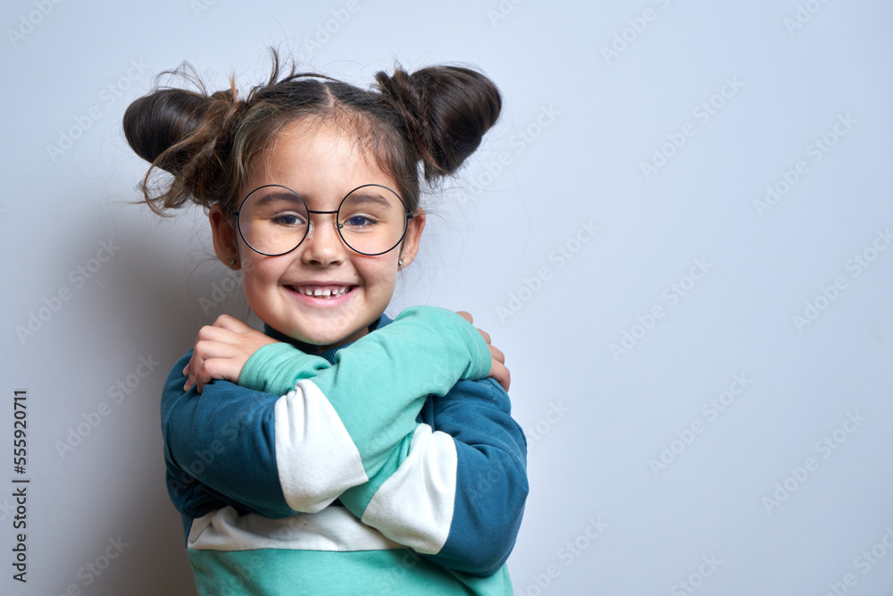 Little girl hugging herself and smiling isolated on white studio background. self love and self care concept Little girl hugging herself and smiling isolated on white studio background. self love and self care concept