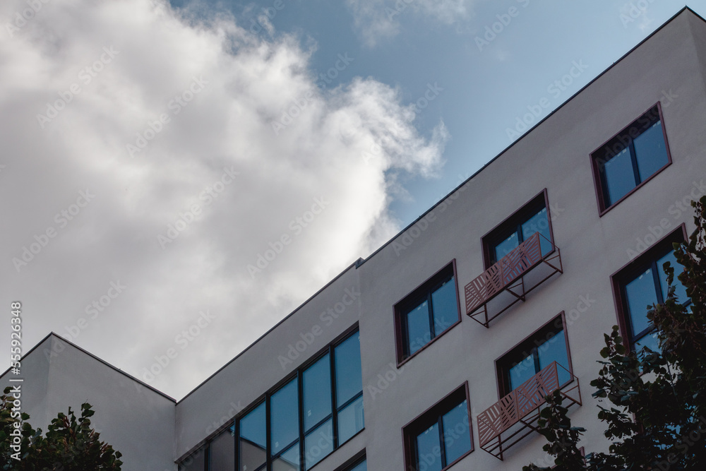 Modern residential building facade architecture details. White walls with blue windows on cloudy sky Modern residential building facade architecture details. White walls with blue windows on cloudy sky
