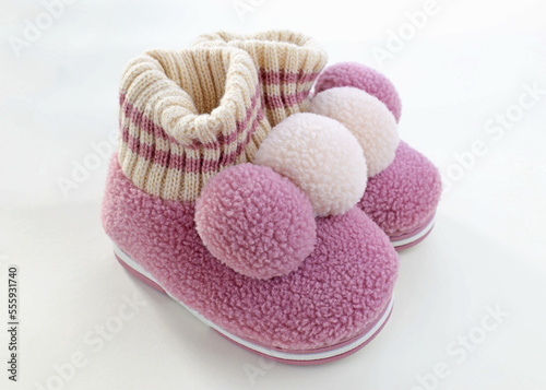 Woolen house children's slippers with balabon. Pink warm slippers for girls. A pair of child's shoes for cold weather on a white background.