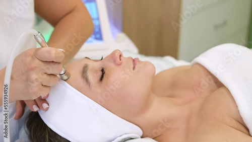 The cosmetologist makes the procedure Microdermabrasion of the skin of the face of a beautiful, young woman in a beauty salon. Cosmetology and professional skin care. Slow motion horizontal video