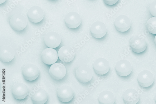 Abstract colored balls background. Multi-colored taw toy scattered on bright paper. Base for design nice backdrop, wallpaper, poster. Noisy surface texture