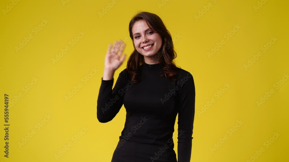 4k slow motion video of cute girl waving hello on yellow background. 4k slow motion video of cute girl waving hello on yellow background.