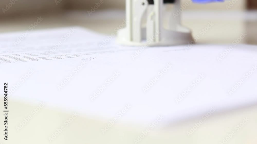 A man's hand signs a document with a pen and puts a stamp, seal A man's hand signs a document with a pen and puts a stamp, seal