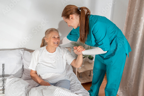Nurse helping an elderly woman at her home. Solicitous professional medical female staff caring in a geriatric institution with a senior patient. Lifestyle
