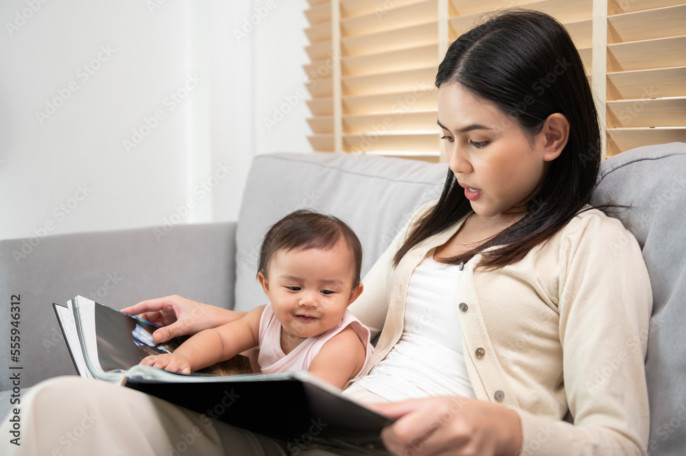 Beautiful mother reading a book to baby girl at home Beautiful mother reading a book to baby girl at home
