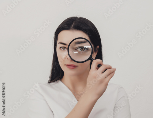 The woman looks into the magnifying glass. One eye enlarged