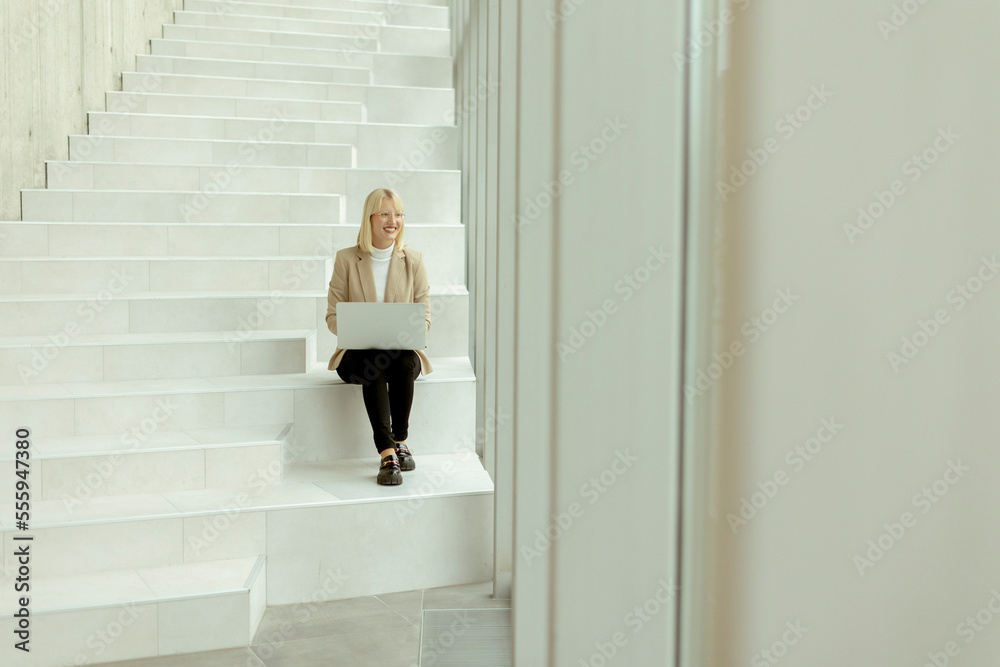 Businesswoman with laptop on modern office stairs Businesswoman with laptop on modern office stairs